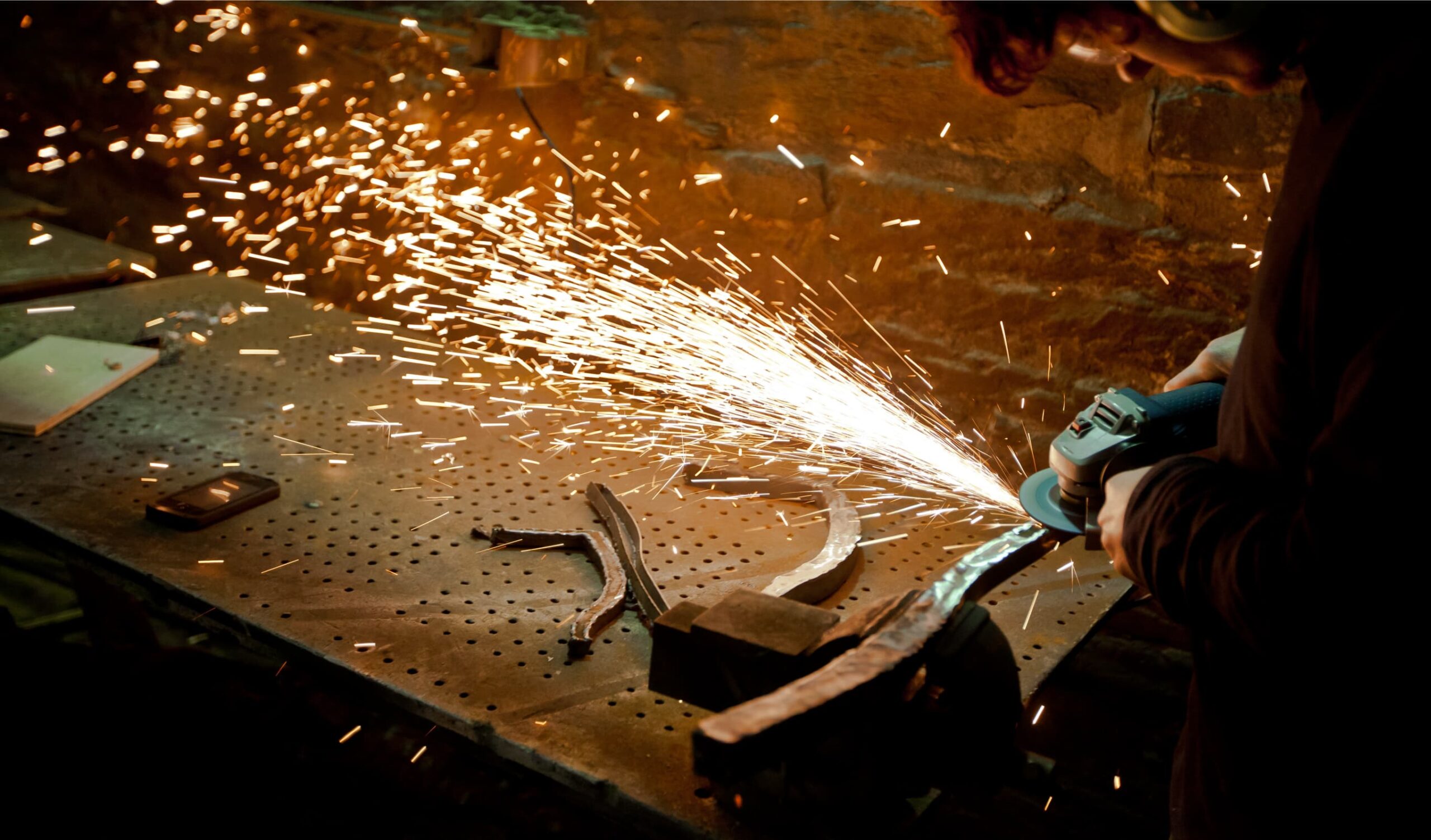 Person grinding metal at table in workshop.